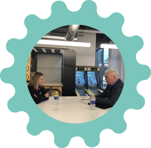 Man and woman at white conference table within a blue gear