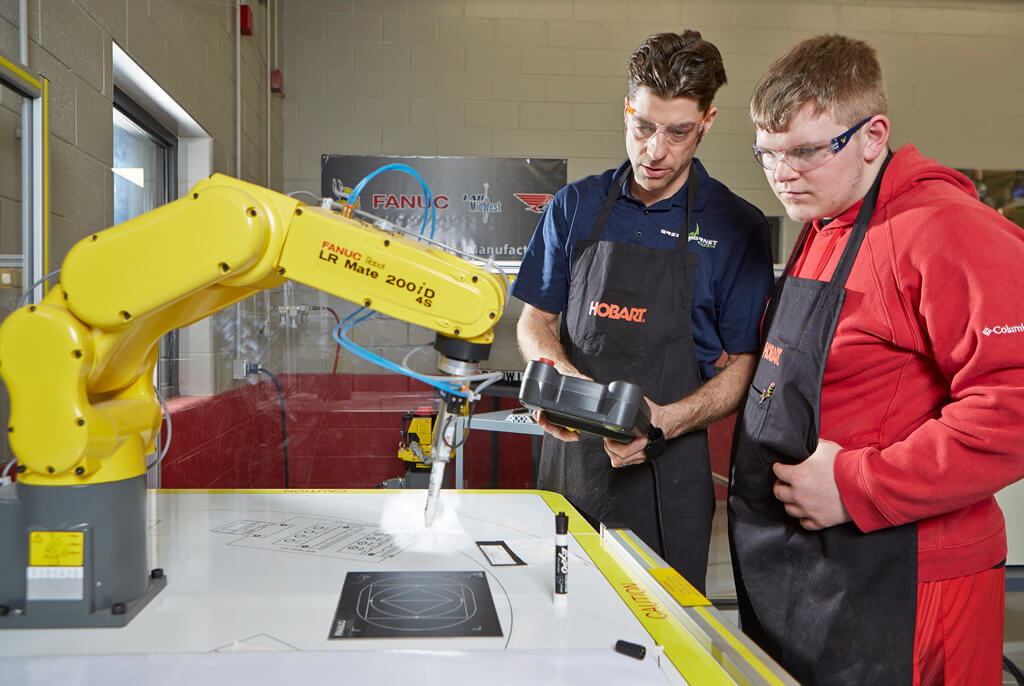 Men near yellow robotic arm.