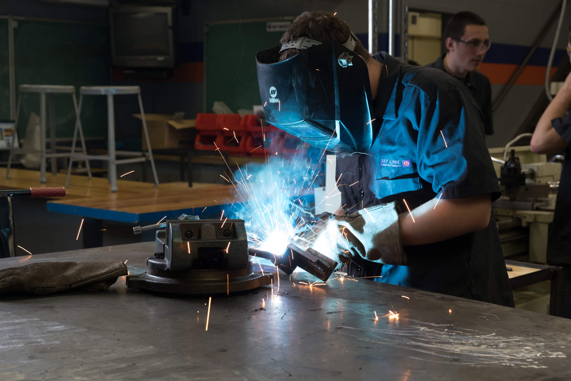 Person in blue welding with white glow